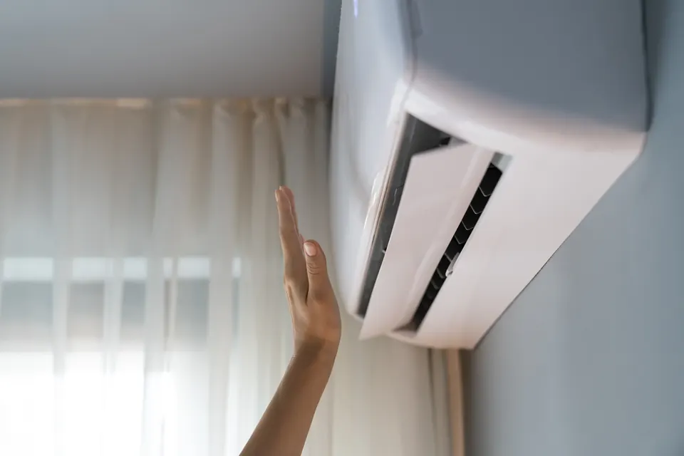 Main qui sent l’air frais soufflé par une climatisation murale réversible