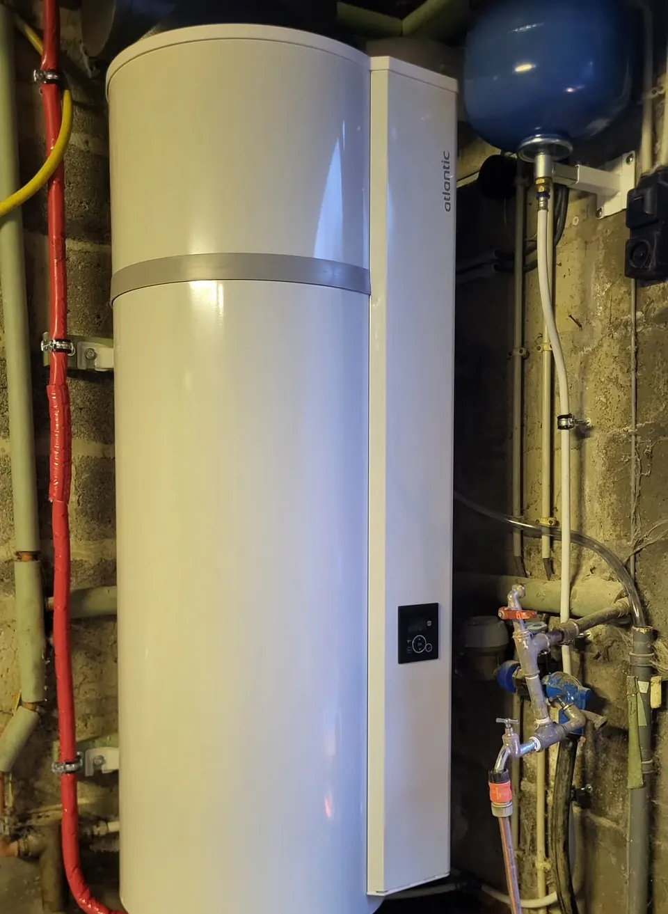 Chauffe-eau thermodynamique Atlantic blanc fixé au mur d’une cave