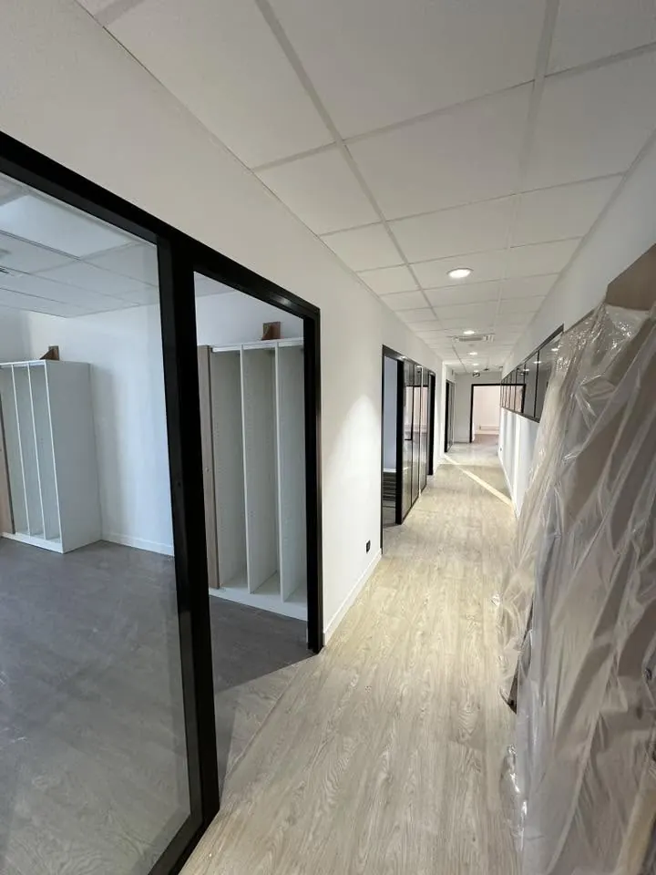 Couloir de bureaux neufs avec faux plafond blanc et cloisons vitrées noires