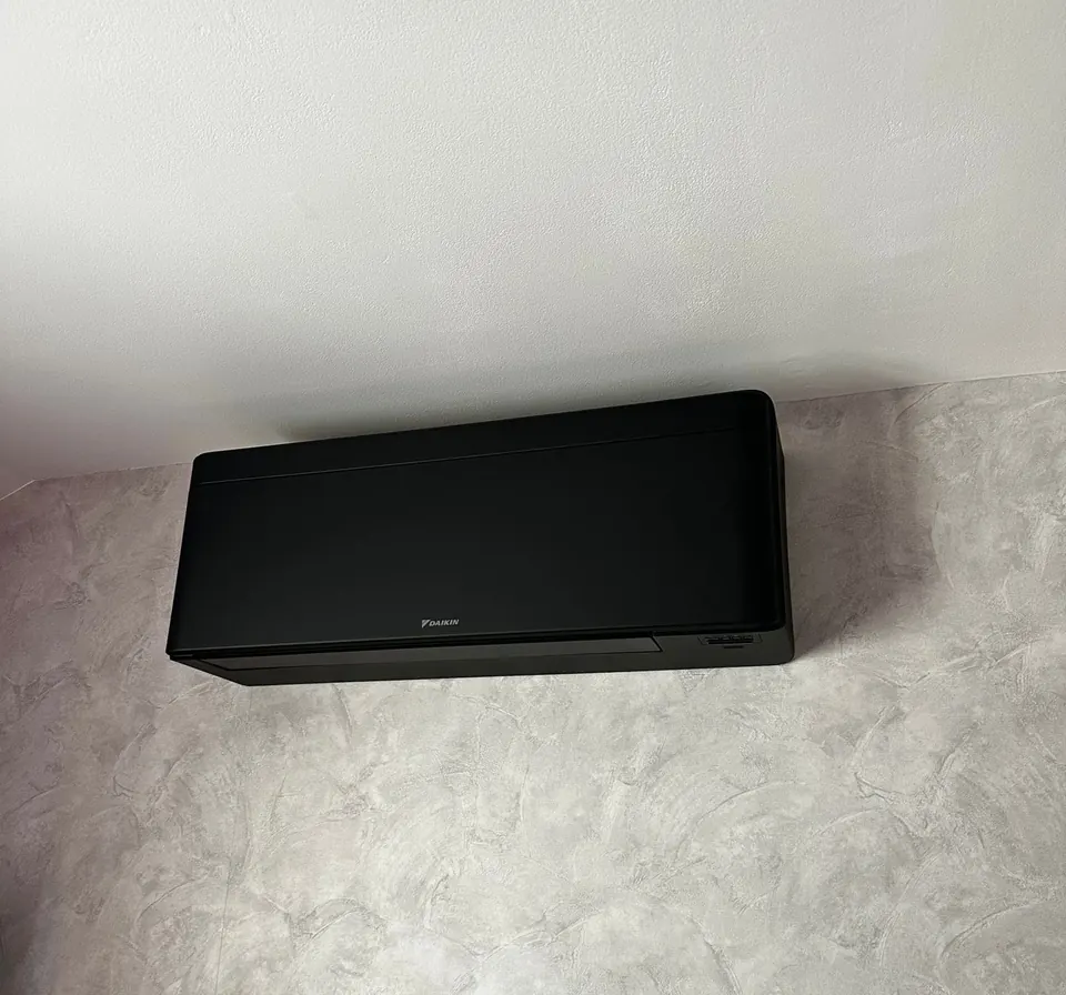 Unité intérieure de climatisation Daikin noire fixée sur un mur en béton ciré gris