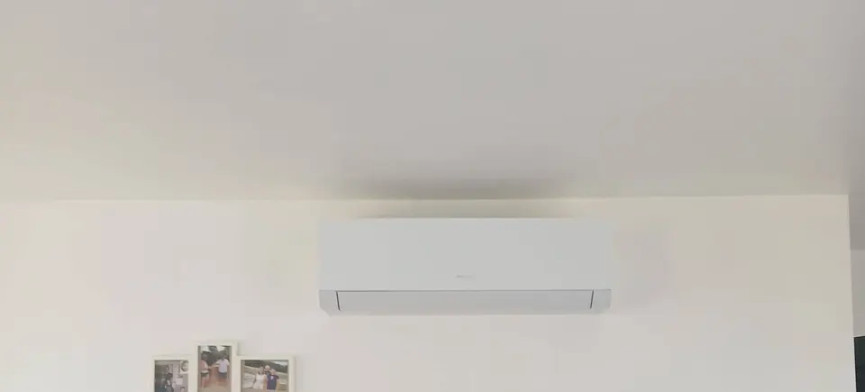 Climatiseur mural blanc sous le plafond d’un séjour