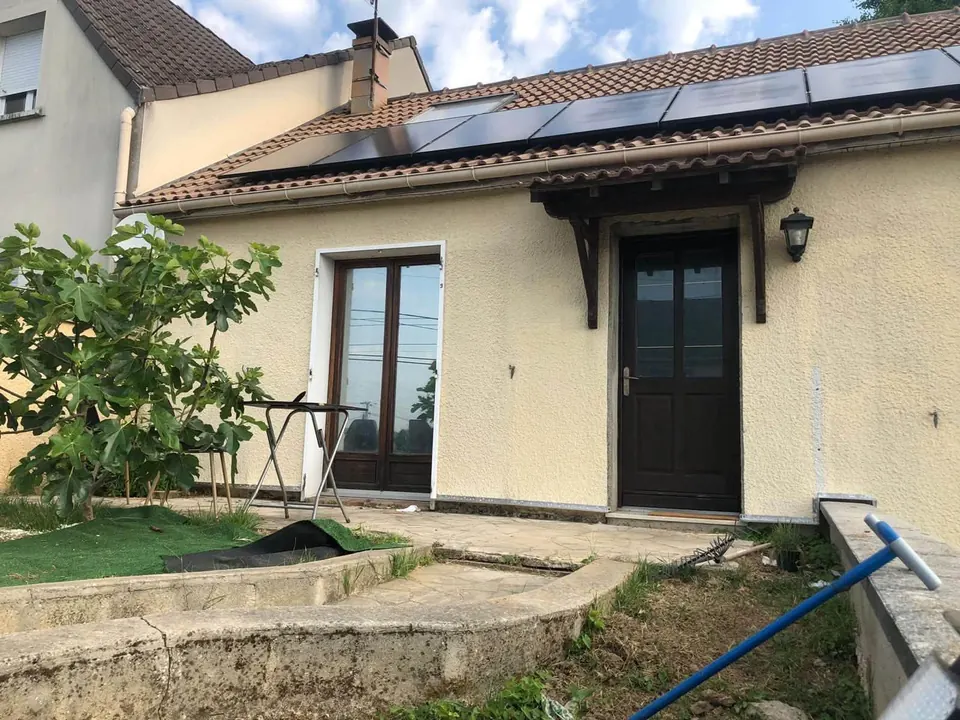Maison individuelle avec une rangée de panneaux solaires noirs sur un toit en tuiles