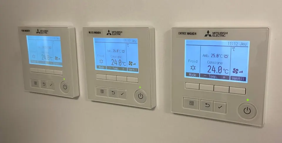 Trois commandes murales Mitsubishi Electric réglées sur 24 degrés, étiquetées entrée, milieu et fond magasin